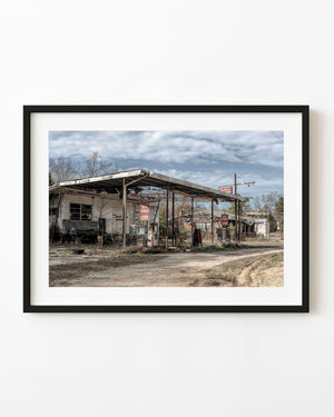 Abandoned gas pumps stand beneath a rusted canopy at a Georgia roadside station in a colour photograph