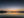 Sailboat reflected on calm coastal water at dawn