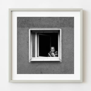 Elderly woman watching street parade from apartment window in Frankfurt