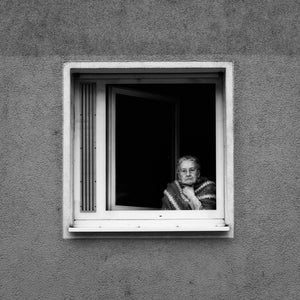 Black and white portrait of elderly woman leaning from window Germany