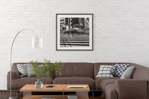 Living room with a brown sectional sofa, wooden coffee table, and framed artwork on a white brick wall.