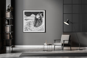 A massive rock wall stands above ice beneath a dark clouded mountain sky