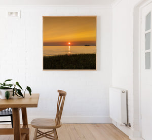 A square landscape photograph captures soft orange sunset light over Lake Superior