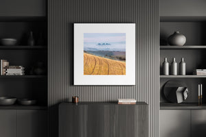 Warm farmland contrasts with cool hazy hills in a peaceful Tuscany photograph