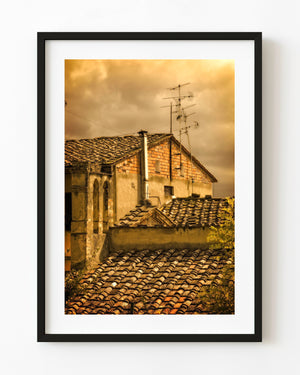 Golden light falls across weathered Tuscan rooftops and village walls
