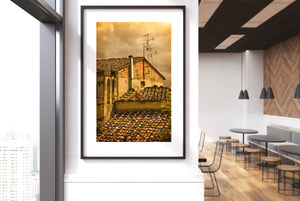 A vertical colour photograph captures golden Tuscan rooftops beneath clouds