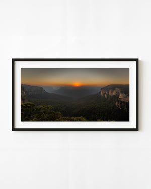 The rising sun glows above forested cliffs at Govetts Leap in Australia’s Blue Mountains