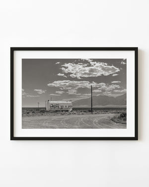 A graffiti-covered water tank stands beneath scattered clouds in rural Nevada