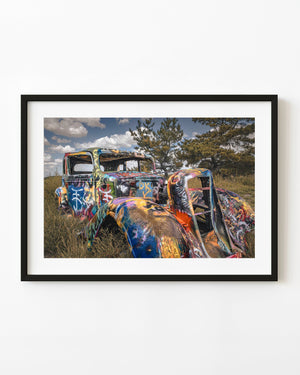 A graffiti-painted vintage car rests among grasses at Texas Bug Ranch