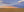 Golden farmland stretches toward distant grain cars under blue and peach evening clouds