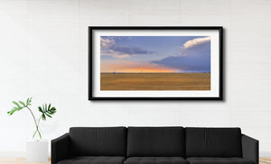 A long train forms a thin line across the Canadian prairie at sunset