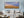 A panoramic landscape photograph captures wheat-coloured fields and a sunset train