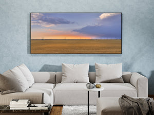 A panoramic landscape photograph captures wheat-coloured fields and a sunset train