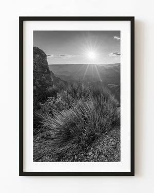 A sunburst shines above the Grand Canyon South Rim in a black and white landscape photograph