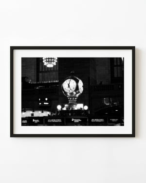 Grand Central Terminal’s illuminated clock stands above the information booth in black and white