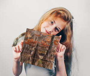 Woman holding a wooden panel with a natural pattern against a plain background