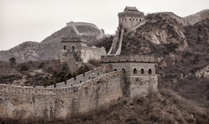 Weathered brick towers and battlements rise across a rocky Chinese hillside