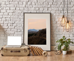 Stone battlements trace a hillside beneath muted sunset light