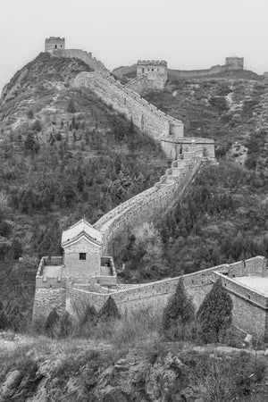 A tiled guardhouse anchors a winding Great Wall stairway across rugged hills