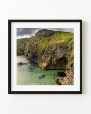 Green cliffs rise above clear turquoise water at Ballintoy in Northern Ireland