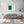 A simple green shutter sits off-centre against a bright white boarded façade