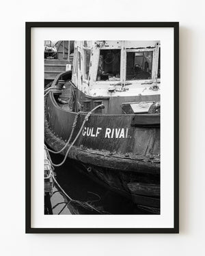The weathered Gulf Rival tugboat rests beside a British Columbia dock in black and white