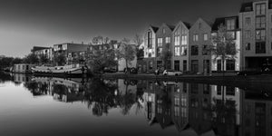 Gabled buildings and waterside trees mirror across a quiet Haarlem canal
