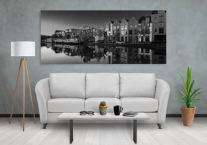 Repeating rooflines and windows form symmetrical reflections along a Haarlem waterway