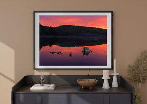 An Ontario lake reflects wooded hills and warm sunrise colour