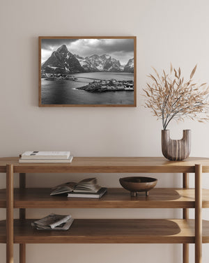 Rippling water fills the foreground beneath an Arctic village and snow-lined peaks