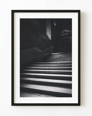 Light catches a Hampton Court staircase rising into deep shadow in black and white