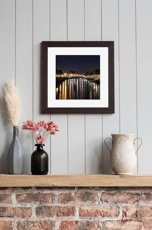 Colour cityscape of Ha’penny Bridge above shimmering River Liffey reflections in Dublin.