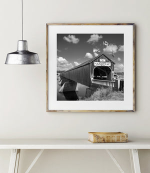 Bright clouds contrast with the dark timber entrance of a New Brunswick covered bridge
