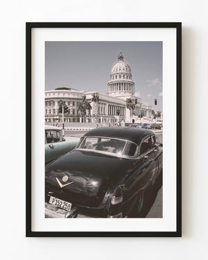 Classic cars on a Havana street with El Capitolio and its domed roof rising in the background.
