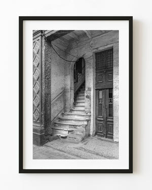 Worn stone staircase beside a tall wooden doorway in Havana, photographed in black and white.