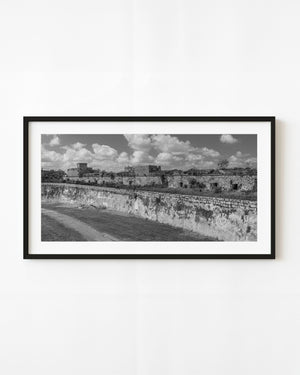 El Morro fort walls in Havana beneath scattered clouds, photographed in black and white.