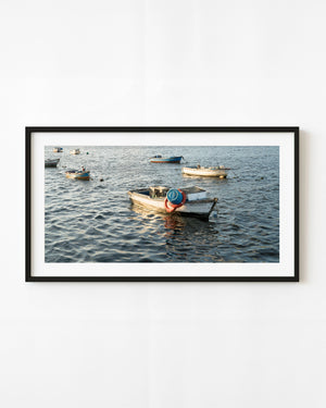 Fishing rowboats float on rippling Havana harbour water, with a white boat in the foreground.