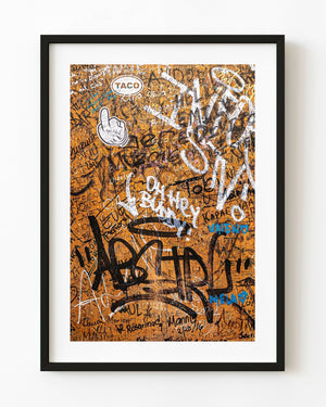 Orange wall at La Bodeguita in Havana covered with overlapping signatures, graffiti and stickers.