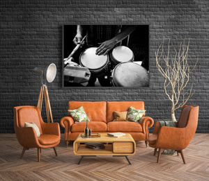 A drumstick and hand above bright drumheads against a dark background in Havana.