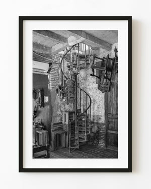 Spiral iron staircase inside a weathered Havana room, photographed in black and white.
