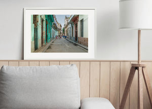 Colour photograph of Havana neighbourhood life among weathered walls, iron grilles and pastel buildings.