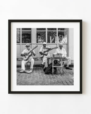 Three street musicians seated with guitars in Havana in black and white
