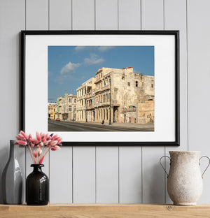 Warm light reveals worn walls and hanging laundry on Havana’s waterfront architecture.