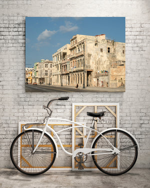 Sunlit Havana architecture with balconies and peeling paint beside a quiet waterfront road.