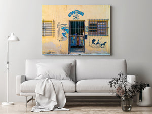 Havana cafe entrance with iron bars, wooden shutters and a painted woman holding a parasol.