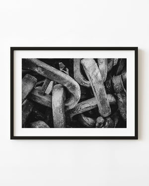 Heavy interlocking chain links fill the frame in a textured black and white industrial close-up.