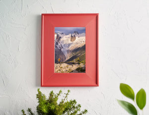 Canadian glacier landscape with jagged snowy peaks and a photographer on a rocky foreground ridge.