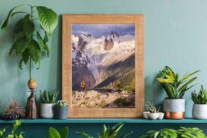 Sunlight reaches snowy mountain slopes above a hiker and alpine trees in Canada.