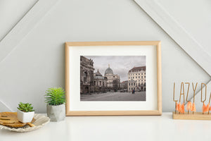 Ornate historic architecture frames a broad cobblestone square beneath a cloudy sky in Germany.