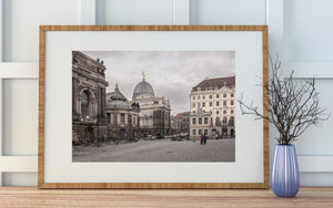 German old town square with historic stonework, parked bicycles and people crossing cobblestones.
